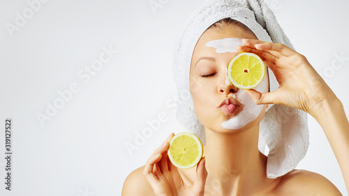Cosmetology, skin care, face treatment, spa and natural beauty concept. Woman with facial mask holds lemons.