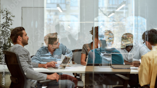 Setting Goals. Group of business people communicating and discussing fresh ideas while sitting together behind the glass wall in the meeting room