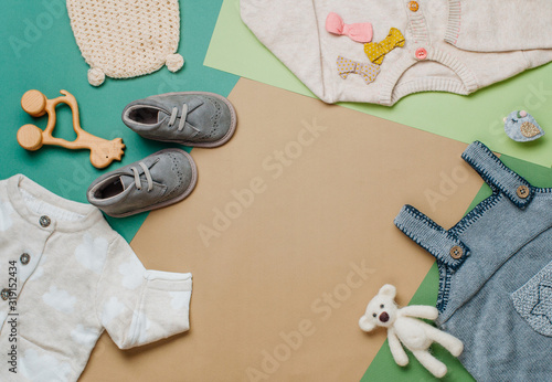 Baby clothes and shoes on neutral background with copy space