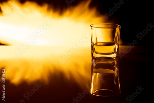 Kielszek z whisky na tle płomieni ognia z efektem odbicia