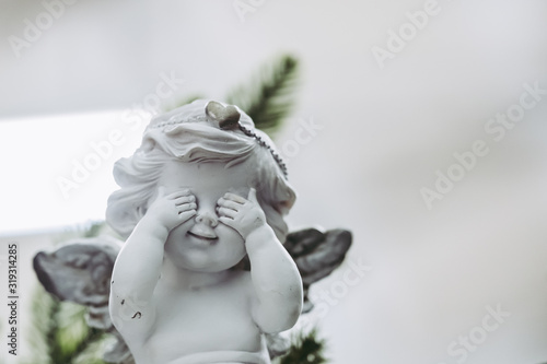 Figurine en terre représentant un ange qui cache ses yeux