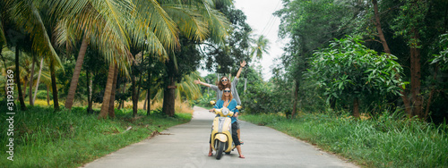 A pair of beautiful women travel by scooter through the jungle in Southeast Asia. Thailand