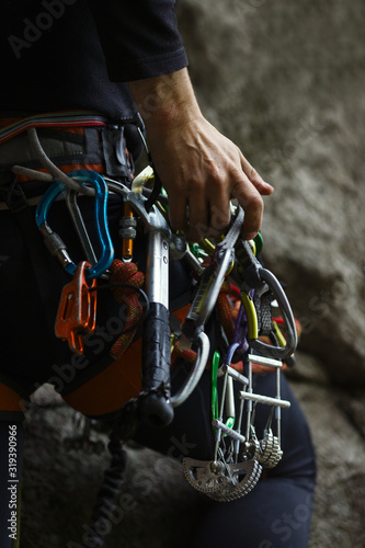 Numerous climbing equipment fixed on the harness of the climber, close-up.