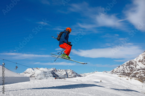 Male skier jumps in snow park against the blue sky