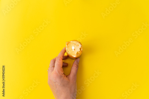Hand with golden candles on yellow background. Wellnes, magic, relax concept. Copy space