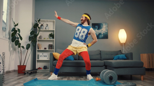 Funny young bearded sportsman dancing with cool energetic moves warming up and exercising at home.