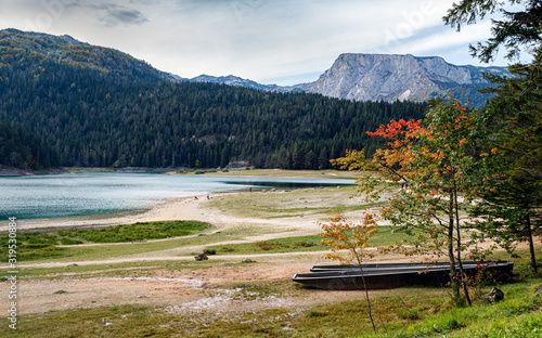 The lake in the mountains surrounded by pine forest, boats on the shore. Calm and tranquility. Black lake in Durmitor national park, Montenegro.