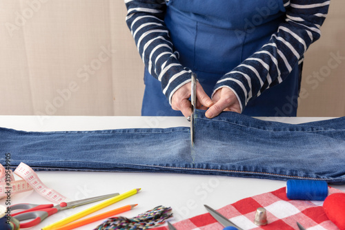 Costurera cortando los pantalones vaqueros