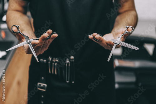 professional barber tool: sharpened scissors held by a haircut master in a modern barber shop. A concept for barbershops, beauty salons and hairdressers