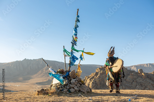 mongolia shaman performed spiritual around Ovoo or Shaman's Shrine at the top of moutain and warm sunset