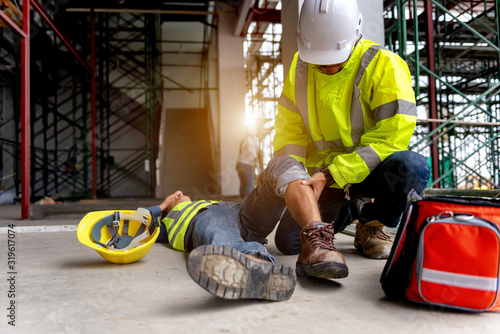 First aid support accident at work of construction worker at site. Builder accident falls scaffolding on floor, Safety team helps employee accident.