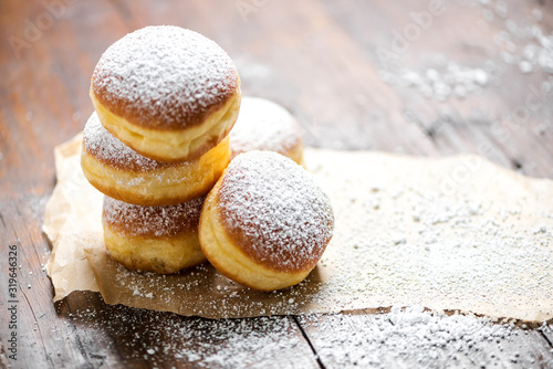 Close-up of donuts (Berlin pancakes) dusted with powdered sugar served on a rustic wooden table