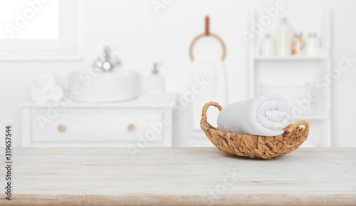 Towel in basket on wooden table over blurred bathroom background