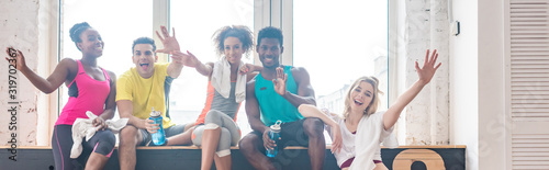 Panoramic shot of multicultural zumba dancers waving hands in camera in dance studio