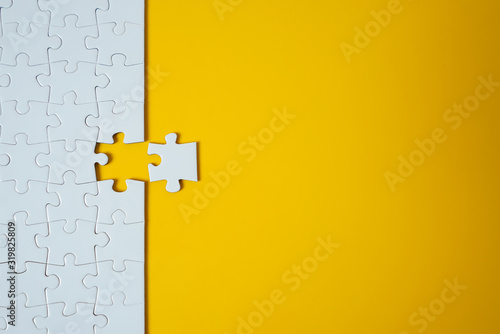 White jigsaw puzzle on yellow background. Team business success partnership or teamwork