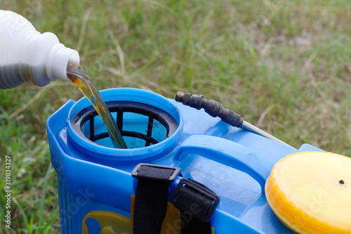 pouring herbicide water from bottle into tank sprayer