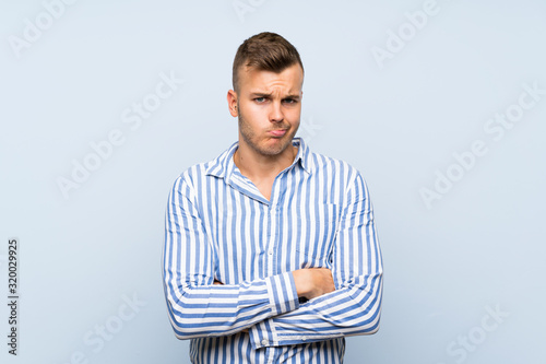 Young handsome blonde man over isolated blue background feeling upset