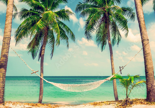 Beautiful beach. Hammock between two palm trees on the beach. View of nice tropical beach with palms around. Holiday and vacation concept. Tropical beach. Beautiful tropical island in Thailand.