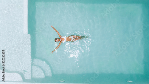 Woman relaxing in clear pool water in hot sunny day on Bali villa