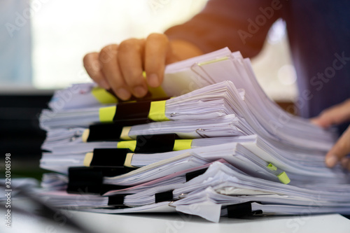 Stacks documents of paper files, Businessman hands working in messy bureaucracy and searching information on office, Accounting budget report file, arranging unfinished of paperwork on busy overwork