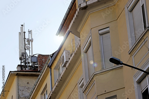 Bird landed on a High Tech Telecommunication Antenna Tower mounted on a building