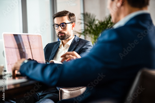 Serious employee sitting next to his coworker