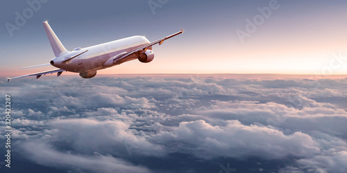 Commercial airplane jetliner flying above dramatic clouds in beautiful light. Travel concept.