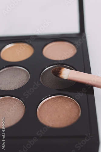 close-up of brush on top of eyeshadow palette with trendy nudes and bronzy tones