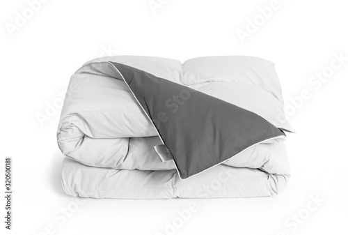 Folded soft white duvet, blanket or bedspread with the gray back side and empty white label, against white background. Close up photo