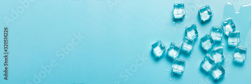 Ice cubes with water on a blue background. Ice concept for drinks. Banner. Flat lay, top view
