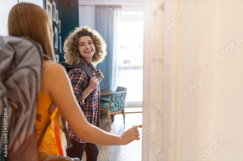 Young women with backpacks arriving to a youth hostel 