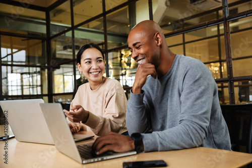 Image of multiethnic young coworkers working on laptops in office