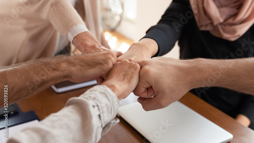 Close up of diverse employees join hands show unity