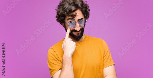 young crazy cool man keeping an eye on you, not trusting, watching and staying alert and vigilant against flat wall