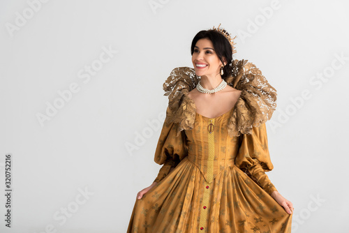 smiling queen with crown looking away isolated on grey