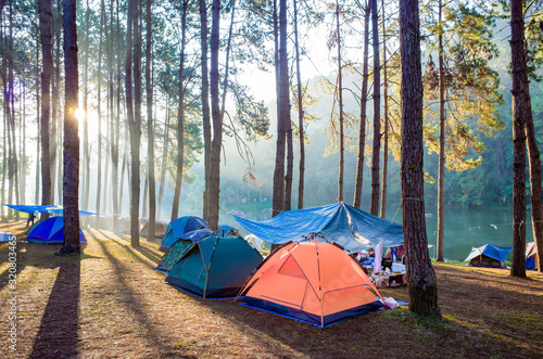 Adventures Camping tourism and tent under the view pine forest landscape near water outdoor in morning and sunset sky at Pang Oung, Royal Forest Park, Mae Hong Son, Thailand