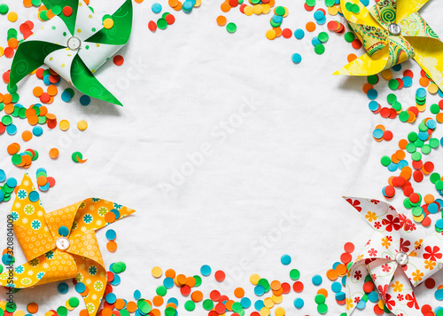 Holiday background with colorful confetti and homemade paper fans, light background, top view. Free space for text