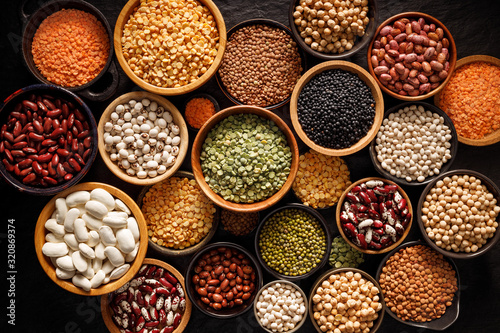 Legumes, a set consisting of different types of beans, lentils and peas on a black background, top view. The concept of healthy and nutritious food