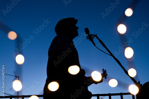 creative outline of a male vocalist singing a song and playing a guitar at spring night. Man musician performing on summer season. Music live concerts concept. Musical, art and creativity with music.