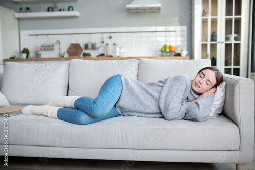 Young girl in a grey sweater having a nap on a sofa