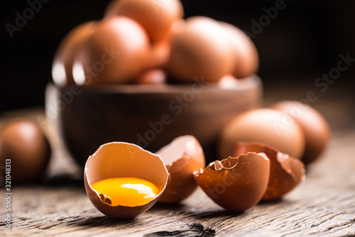 Broken chicken eggs with yolk on wooden table