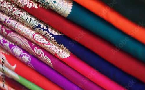 Closeup view of stacked saris or sarees in display of retail shop 