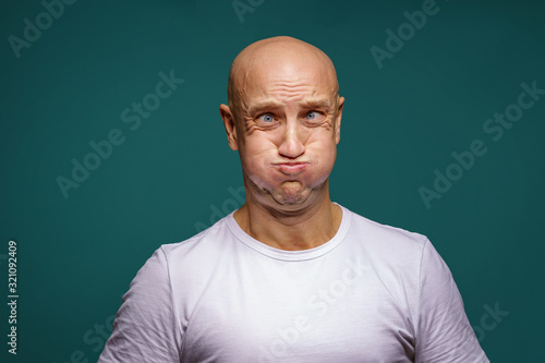 portrait of a bald man puffed out his cheeks on a blue background