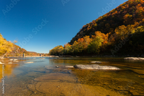 The crystal clear Water of the Potomac River in Harper's Ferry, West Virginia, on a sunny Day with colorful Foliage on Trees
