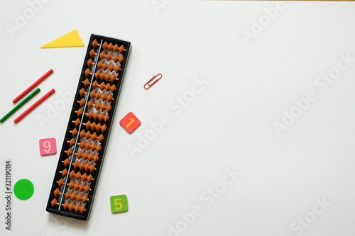 Mental arithmetic and math concept: colorful pens and pencils, numbers, abacus scores on white background, copy space