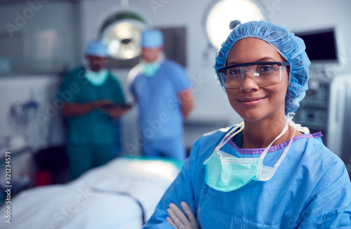 Portrait Of Female Surgeon Wearing Scrubs And Protective Glasses In Hospital Operating Theater