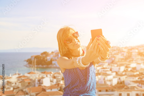 Young woman using cellphone above nice city panorama.