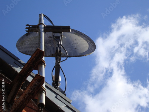 a TV aerial with mesh dish against a blue sky