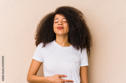 Young african american woman touches tummy, smiles gently, eating and satisfaction concept.