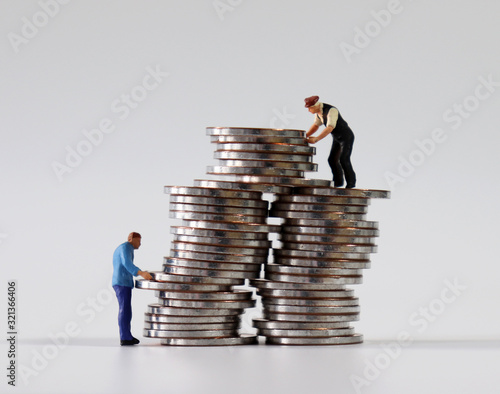 Two miniature men stacking coins.